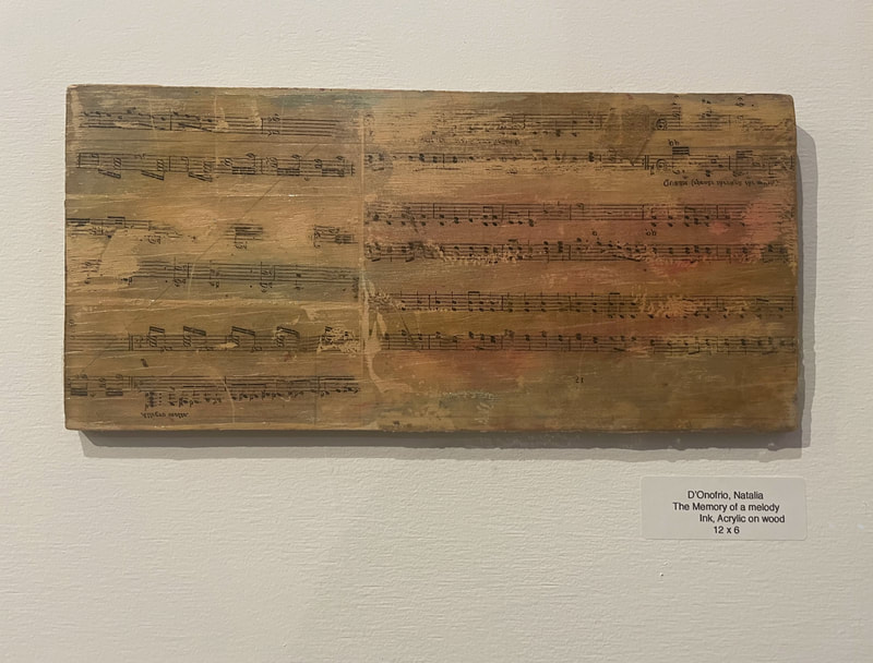 Rectangular artwork, light washes of color in the background, and black musical notes on the foreground on wood
